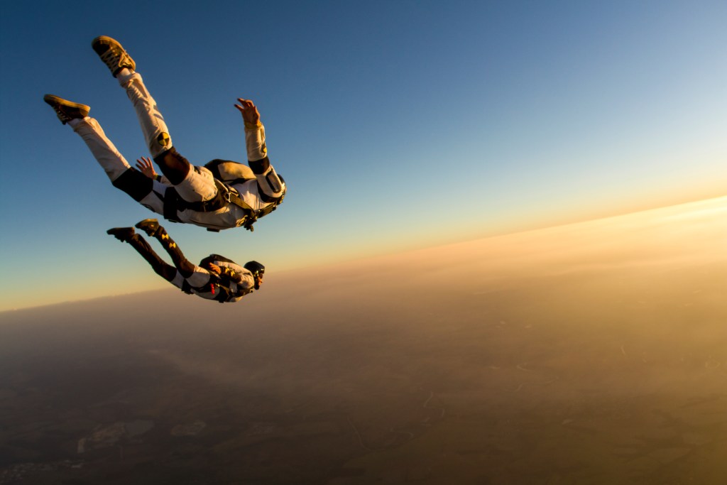 Two skydivers freefalling over breath-taking landscape, capturing the thrill of adventure